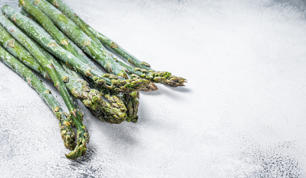 Frozen cold asparagus on a old kitchen table. White background