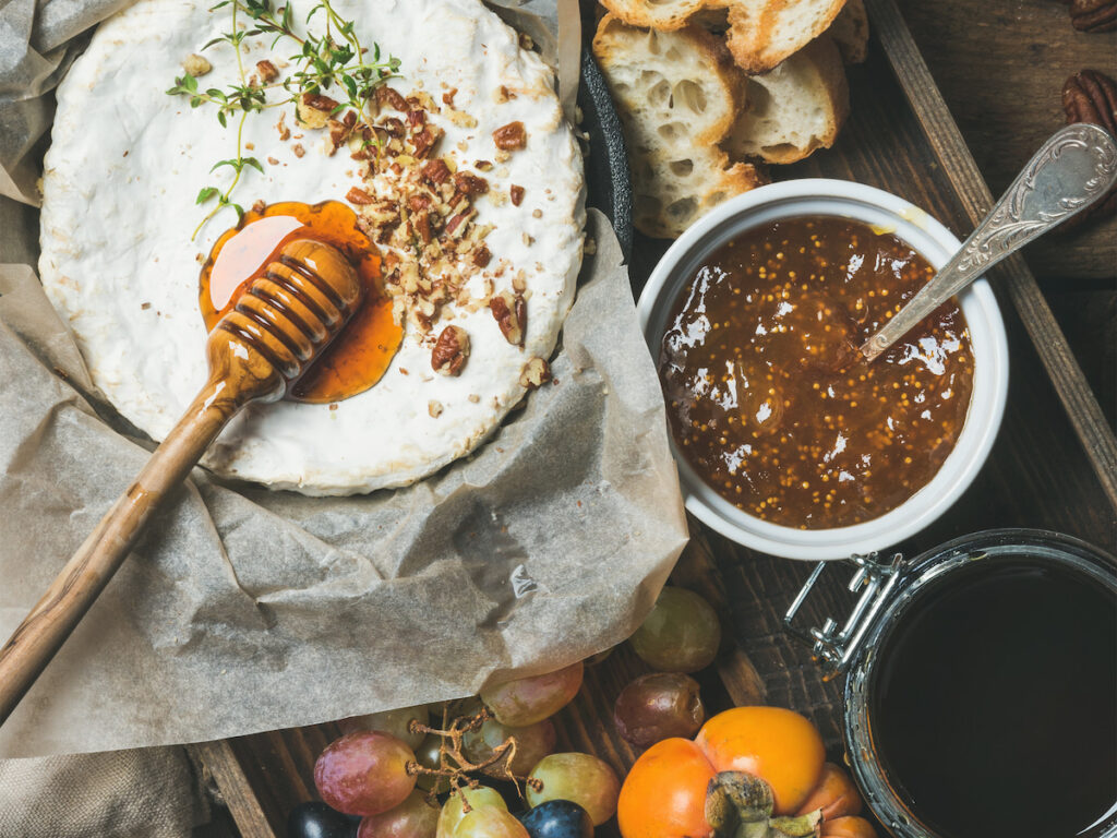 persimmon fig jam on a platter with honey, bread and grapes