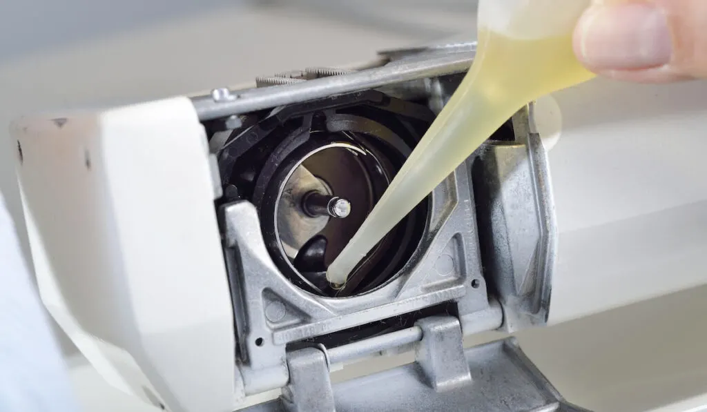 man putting oil in a sewing machine