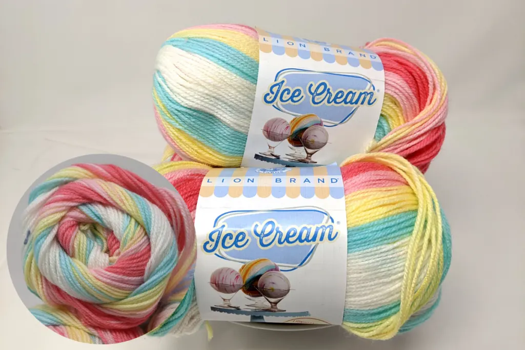 skeins of lion brand ice cream yarn in the tutti fruitti colorway. Small inset circle showing end of one of the yarn skeins