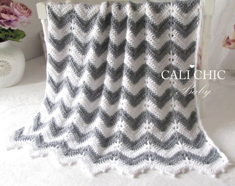 a white crochet blanket with gray zigzag pattern