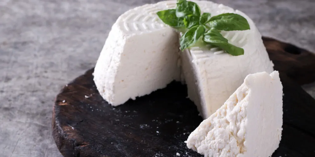 A fresh ricotta with basil leaf on wooden table italian food concept