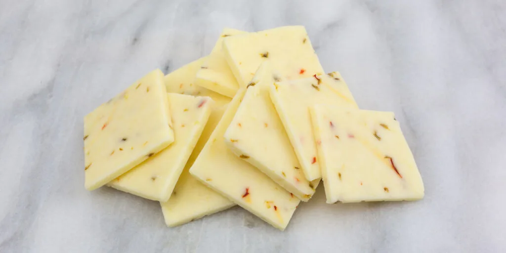 A small pile of fresh pepper jack cheese on a gray marble cutting board