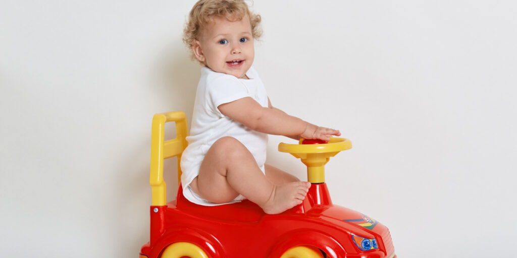 Excited baby toy sitting on red and yellow car