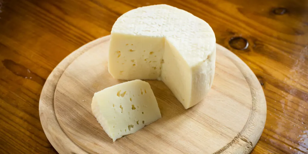 Fresh caciotta, italian cheese on a wooden board