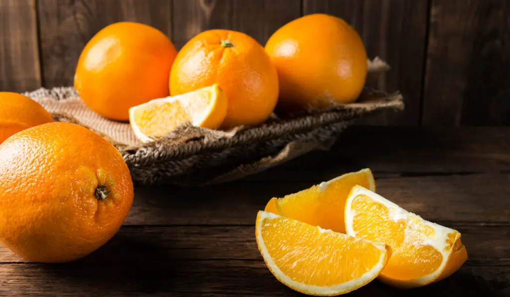 Fresh ripe oranges and slices of oranges on wooden background 