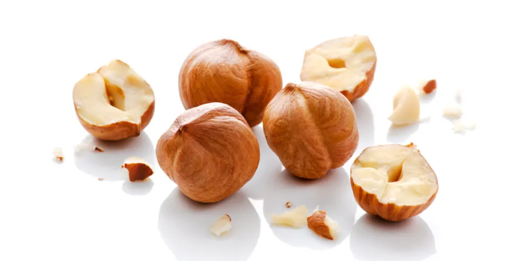 Full and halves of hazelnuts on white background