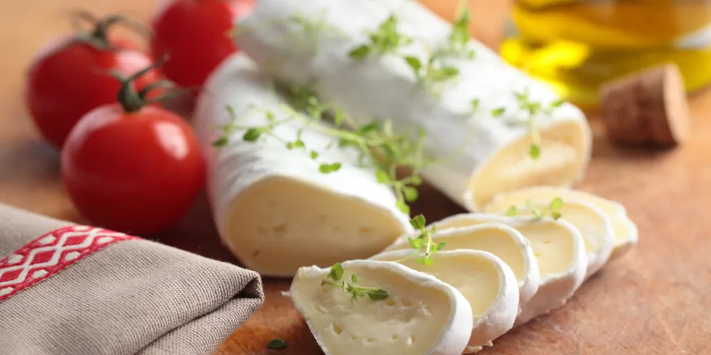 Goat cheese, cherry tomato, and thyme on a wooden cutting board