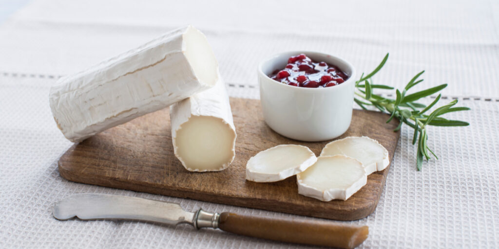Goat cheese on a wooden board on a light background