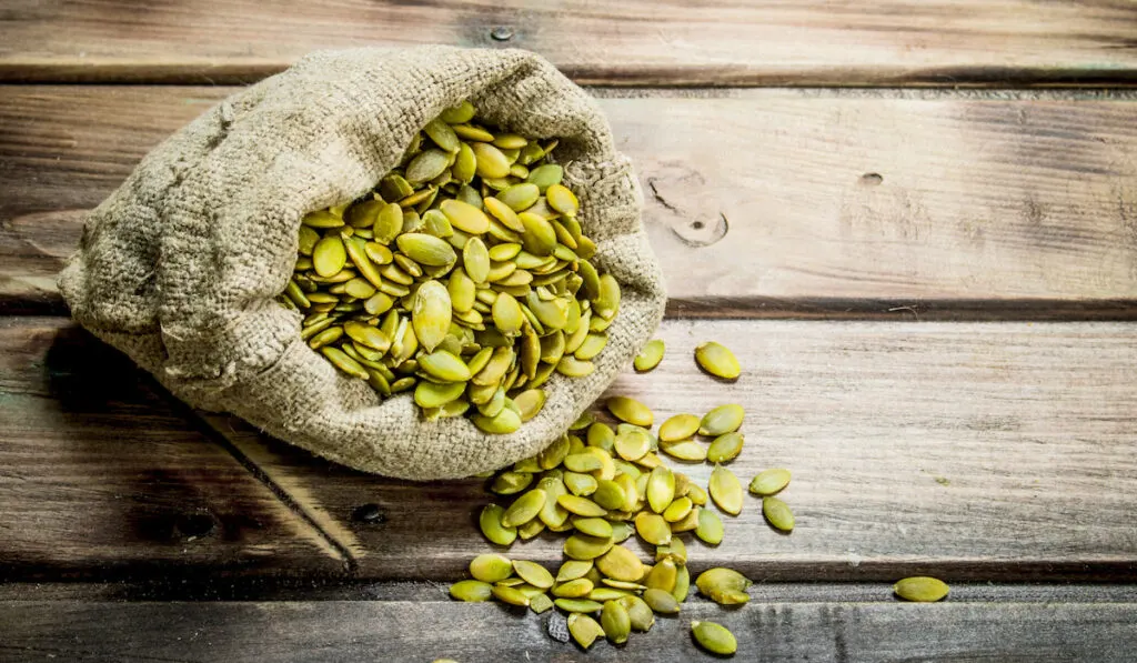 Pumpkin seeds in a bag on wooden table 