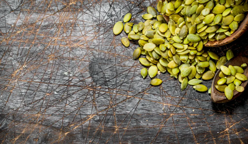 Pumpkin seeds in bowl on wooden background 