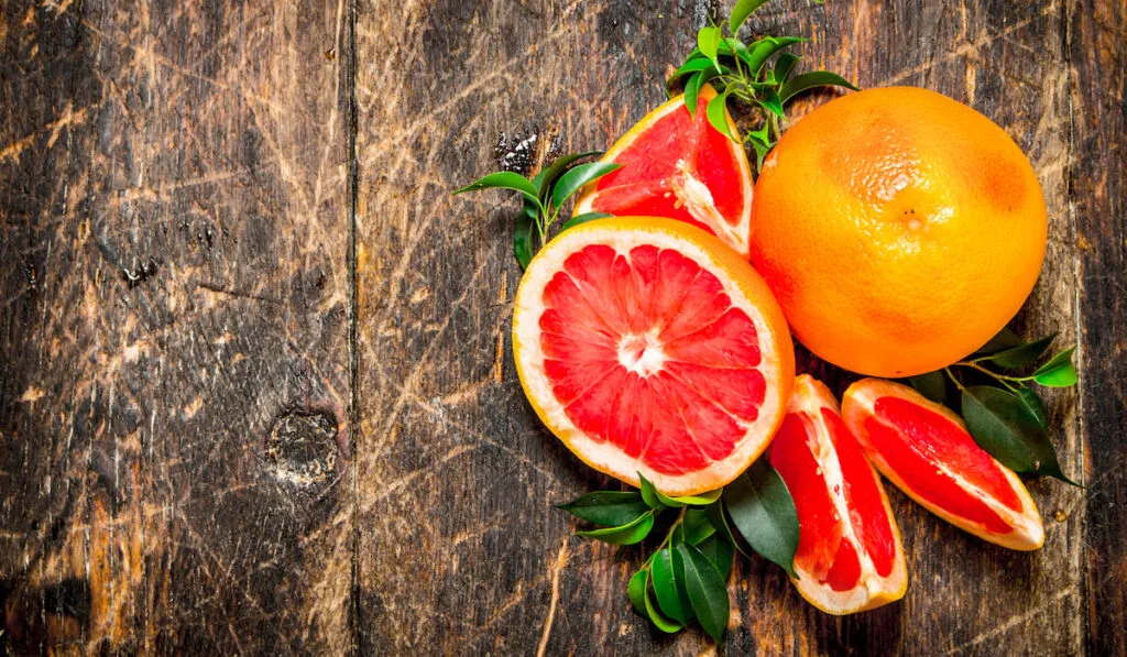 Ripe whole and sliced grapefruits on wooden background