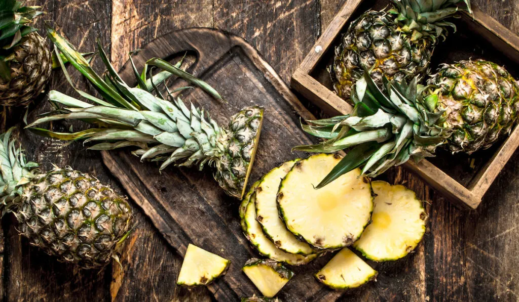 Sliced fresh pineapple on wooden chopboard and background 