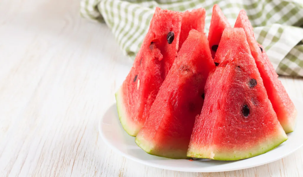 Sliced watermelon on the plate on white wooden background