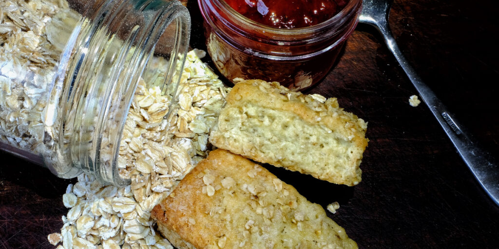 Top view of homemade oat scones with jar of oatmeal and strawberry jam