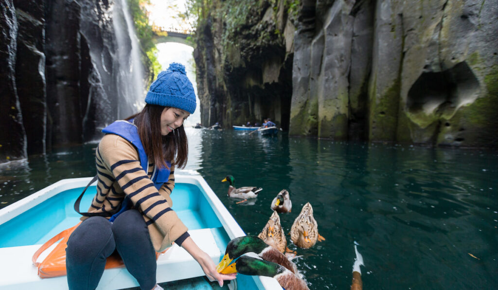 Tourist Woman feeding duck and sitting on boat