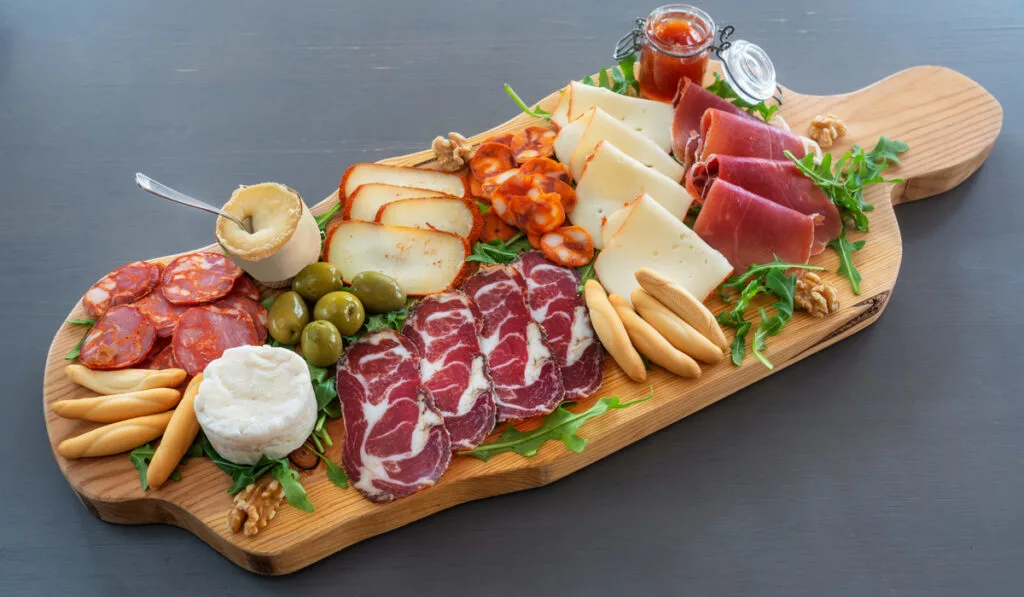 Very colorful tapas board of charcuterie with cheese and smoked meats.