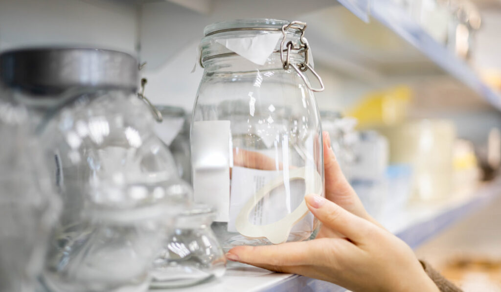 Woman choosing glass jar container for food storage kitchen