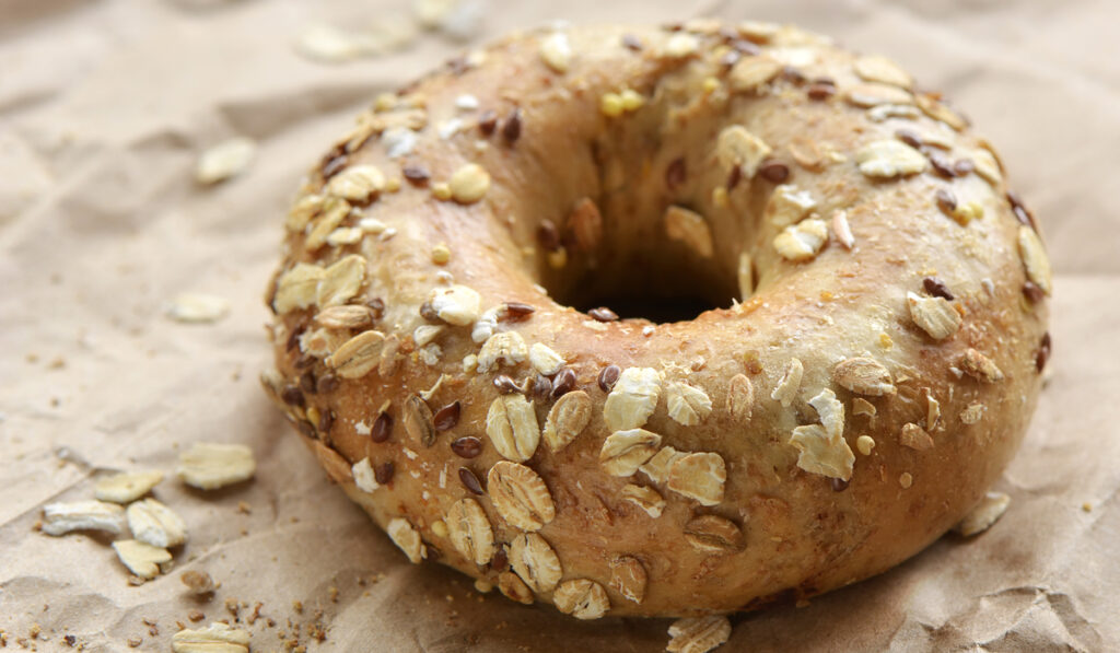  bagel covered in oats and seeds on crinkled brown paper