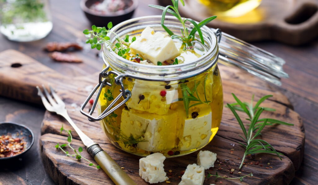 feta cheese in a mason jar with oil olive with some herbs and spices