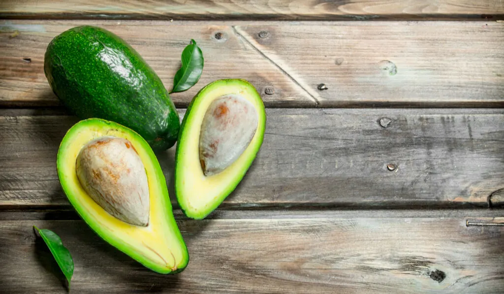 fresh Avocado and avocado slices on wooden table 