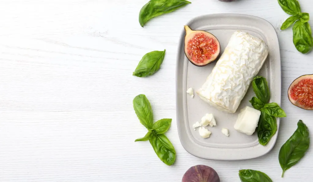 goat cheese on a gray tray with fresh basil and sliced figs 