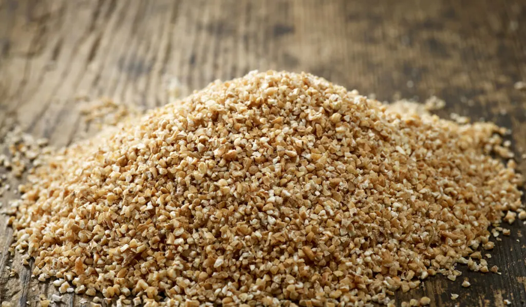 heap of wheat grits on wooden table