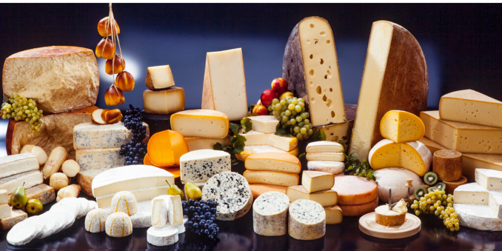 large assortment of international cheese specialties on black background