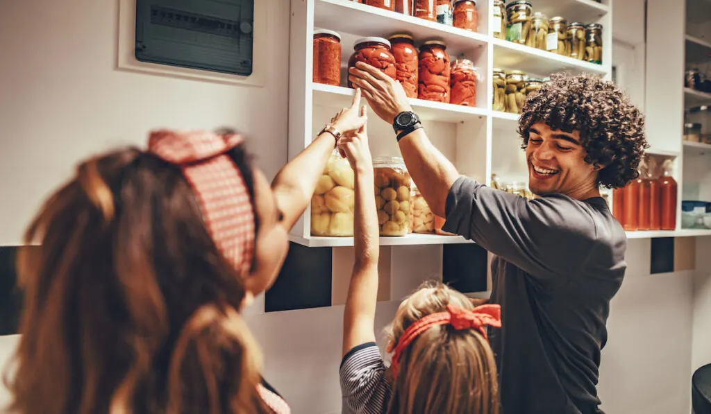 siblings pointing and helping each other in kitchen pantry 