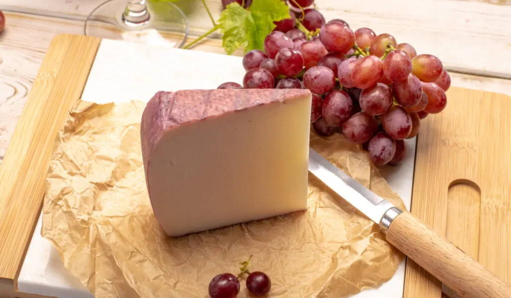 sliced Murcia Al Vino and grapes on wooden chopping board