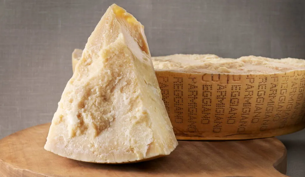 sliced Parmigiano-Reggiano and wheel cheese on the background 