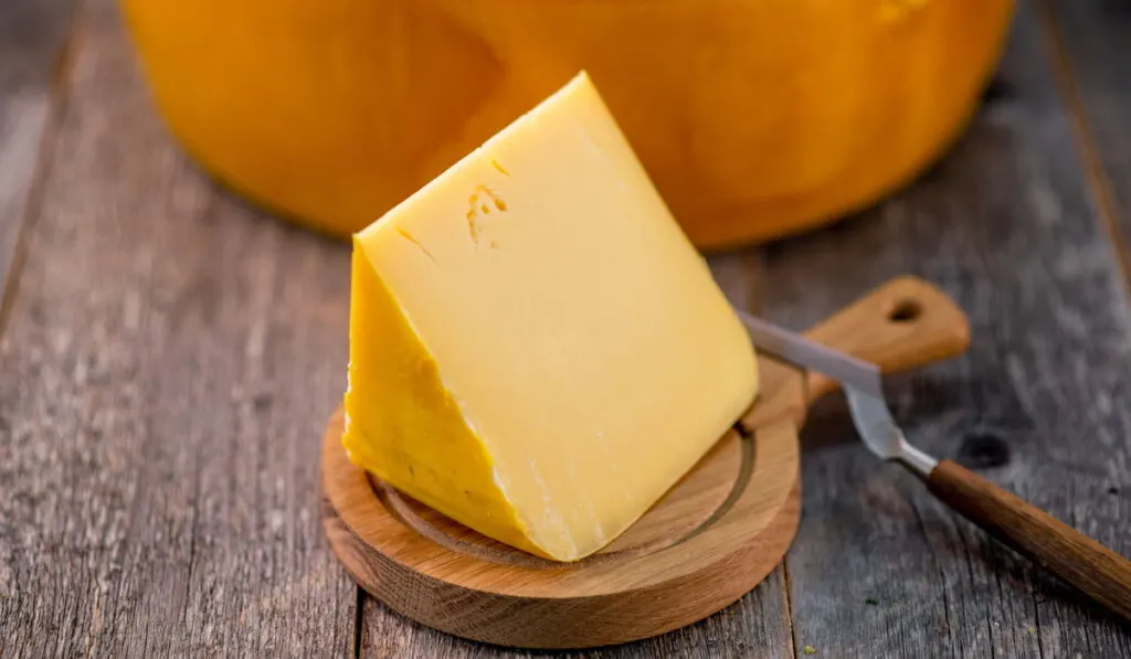 sliced gouda cheese on small wooden board 