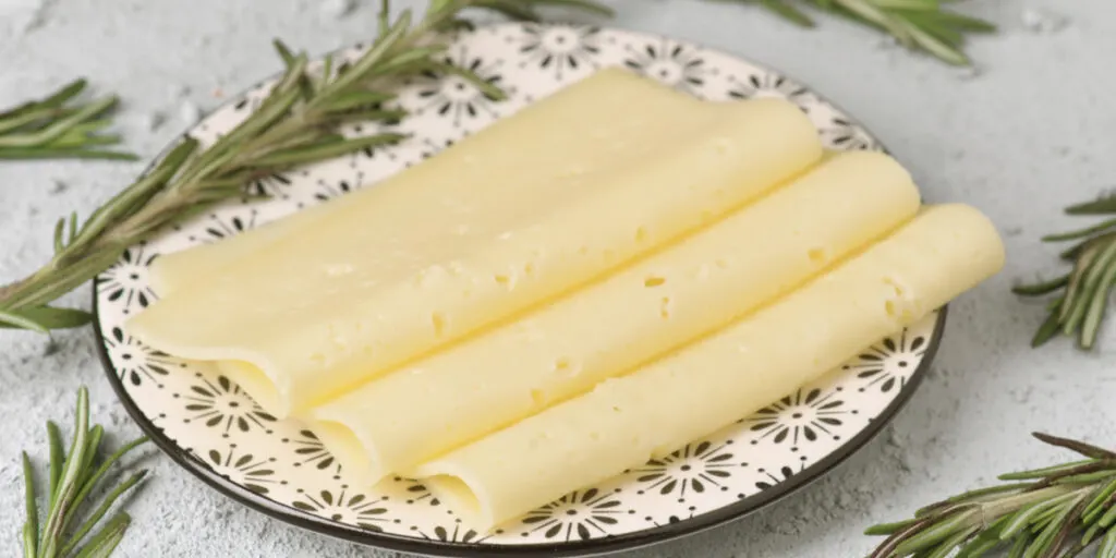 slices of havarti cheese on a plate decorated with rosemary