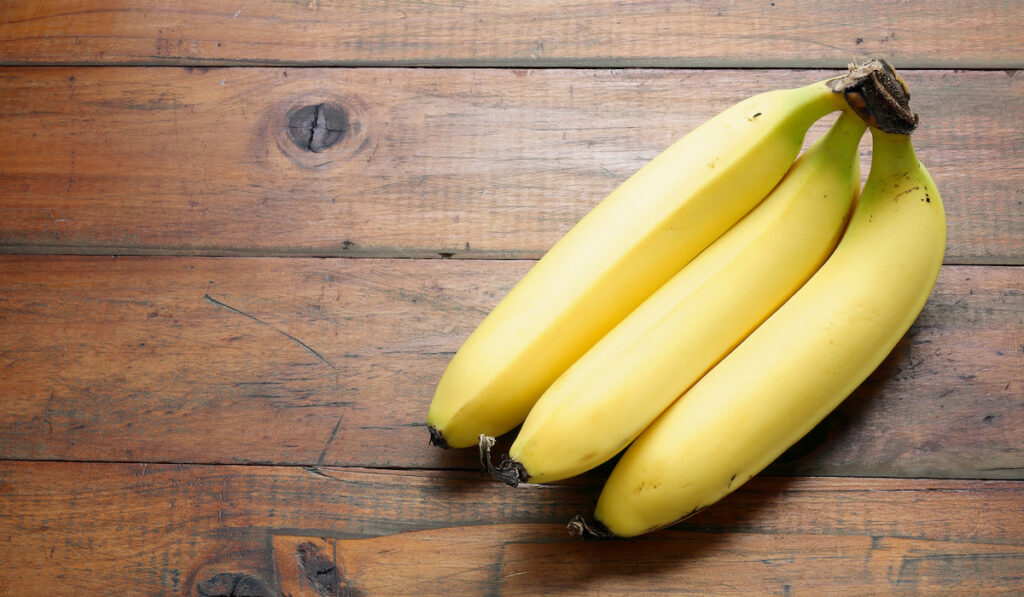 three pieces of yellow banana on wooden table 