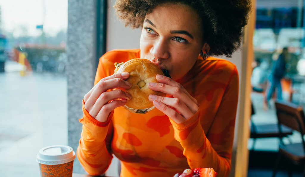woman-sitting-restaurant-eating-bagel