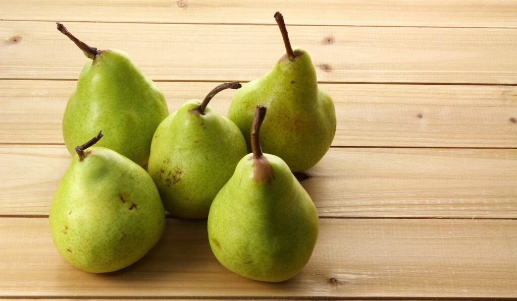 5 pieces of green pears on wooden table 