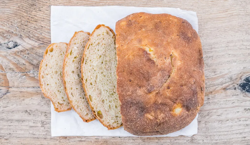 A half of home made village potato bread on wooden background 