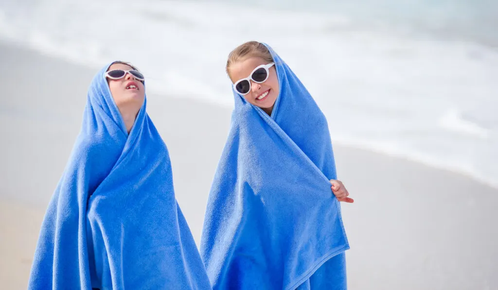 Adorable little girls wrapped in towel at tropical beach