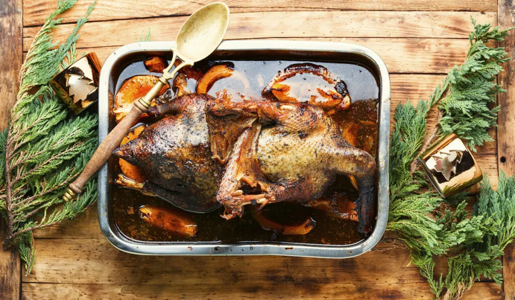 Baked stuffed goose on wooden table 