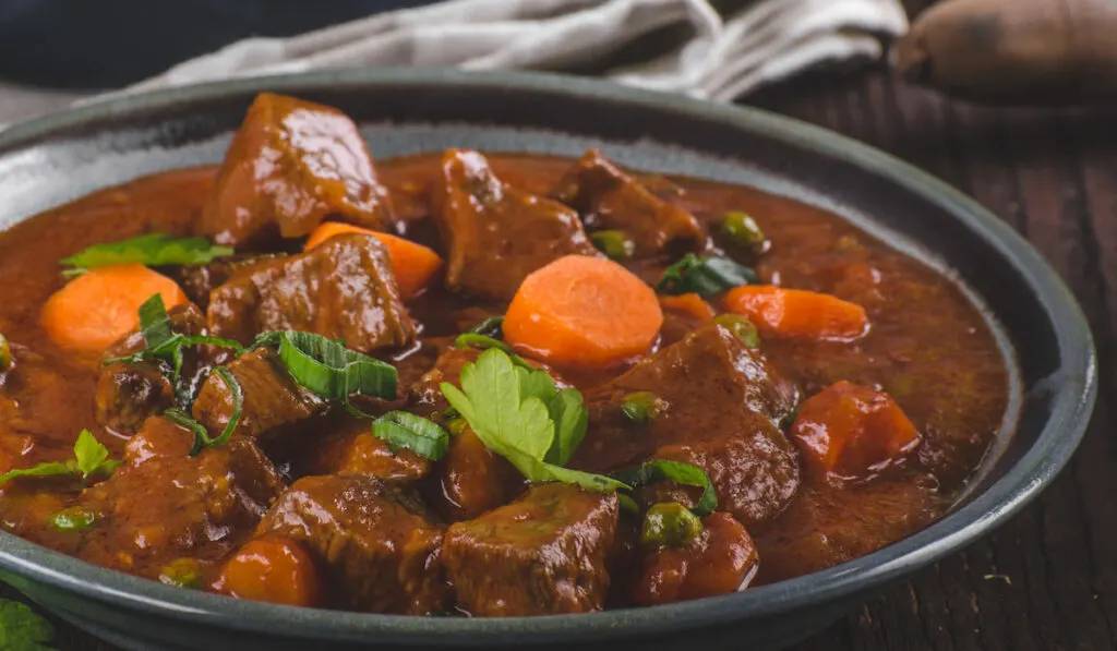 Beef stew with carrots on black bowl 