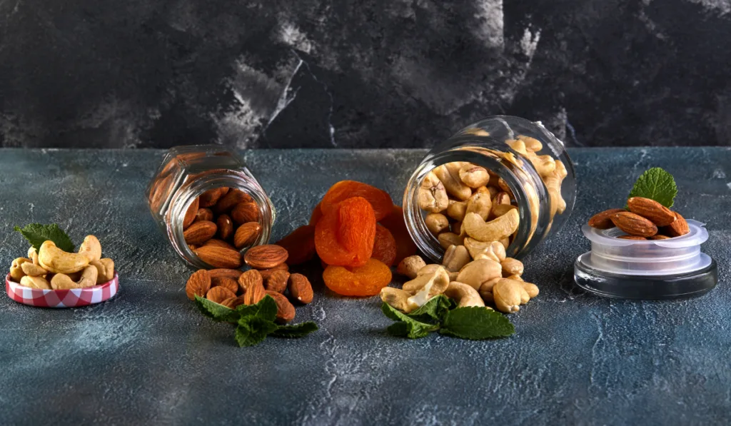 Cashew almonds spill out of transparent cans