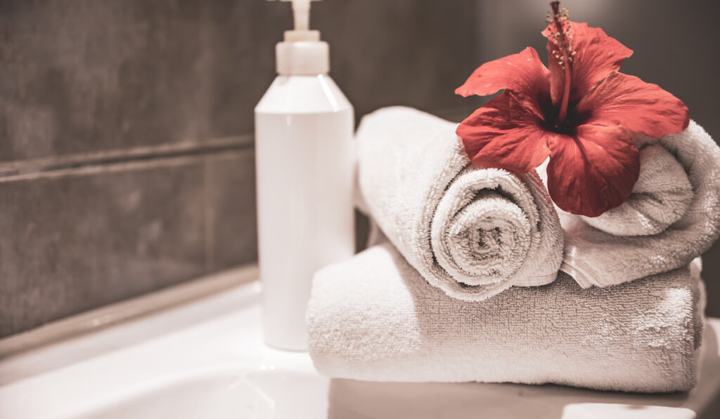 Clean towels, bottle dispenser and flower in the bathroom
