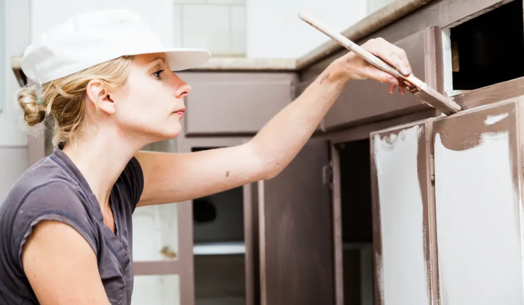Closeup of Woman Painting Kitchen Cabinets
