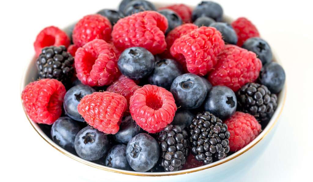 Closeup of a bowl of fresh berries, summer food on white background 