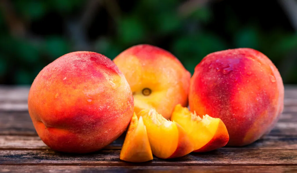 Fresh ripe peaches and slices on wooden table 