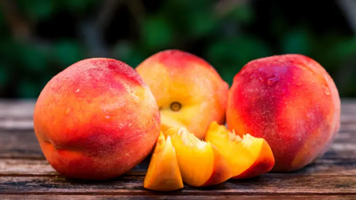 Fresh-ripe-peaches-and-slices-on-wooden-table