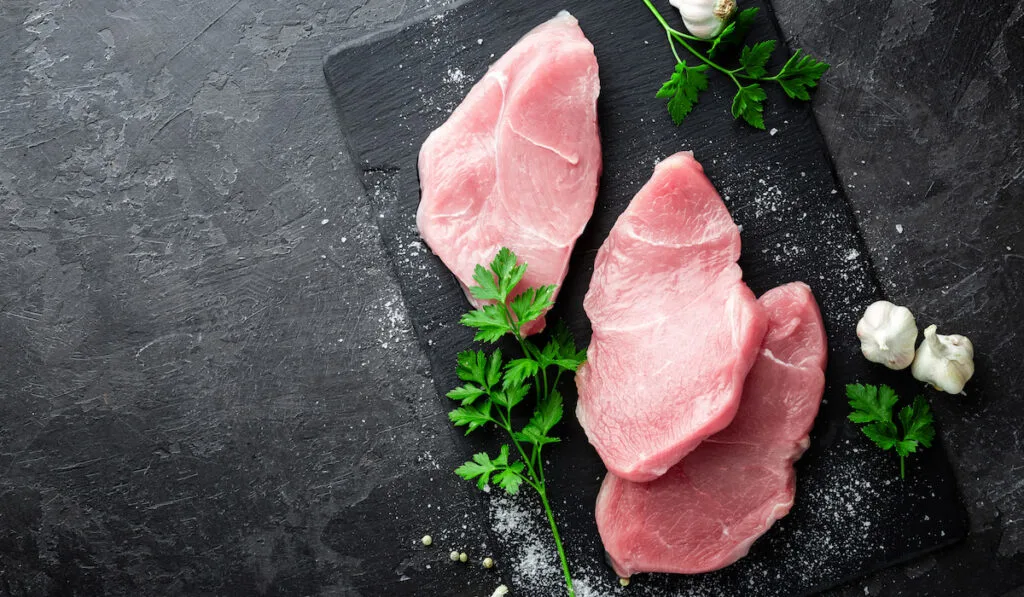 Fresh sliced turkey meat on black board 