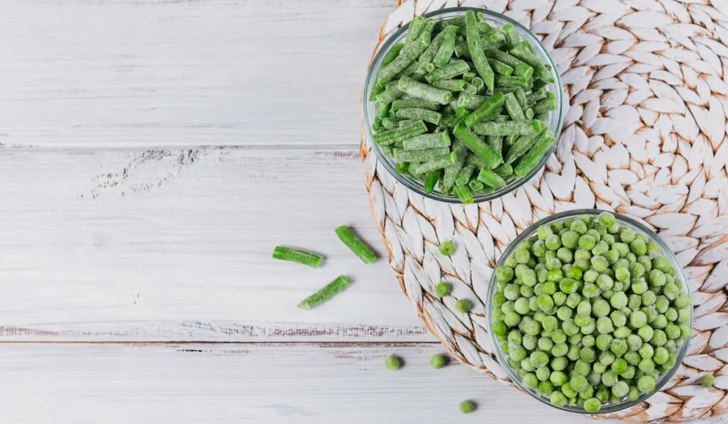 Green peas and cut green beans in bowl on white background 