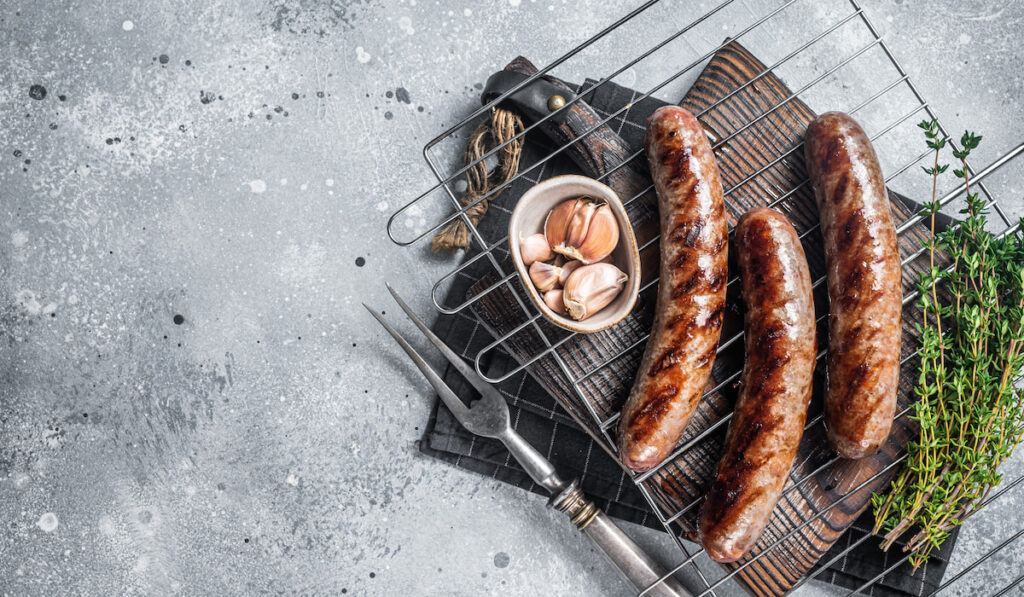 Grilled beef and lamb meat sausages with rosemary herbs on grill 