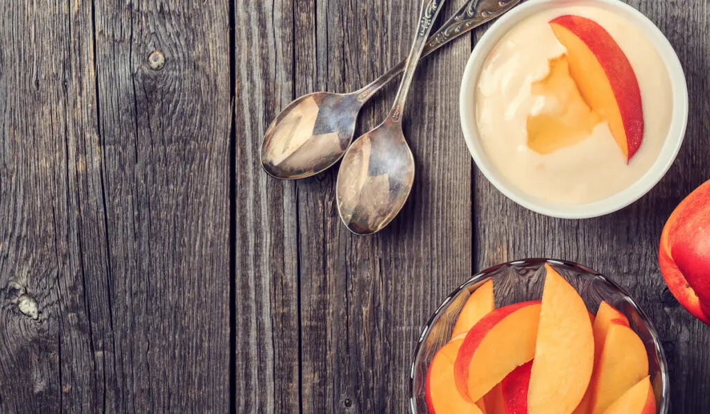 Homemade peach yogurt with fresh peaches on a wooden background 